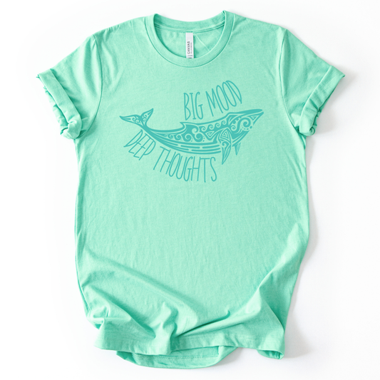 Coastal ocean graphic on a soft unisex heather mint graphic tee. The design features a stylized whale illustration with decorative swirl and line details inside the body, creating a clean sea life look. The phrase Big Mood appears above the whale, with Deep Thoughts arched below, forming a balanced layout that reads clearly from a distance. 