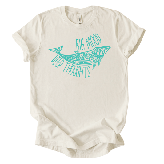 Coastal ocean graphic on a soft unisex heather oatmeal graphic tee. The design features a stylized whale illustration with decorative swirl and line details inside the body, creating a clean sea life look. The phrase Big Mood appears above the whale, with Deep Thoughts arched below, forming a balanced layout that reads clearly from a distance. 