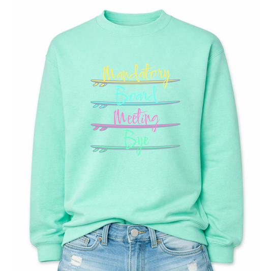 Beach humor graphic on a classic mint green crewneck sweatshirt. The design features stacked lettering that reads Mandatory Board Meeting Bye, with each word separated by illustrated surfboards that act as graphic dividers. The colorful surfboards create a playful coastal layout that reinforces the beach lifestyle theme.