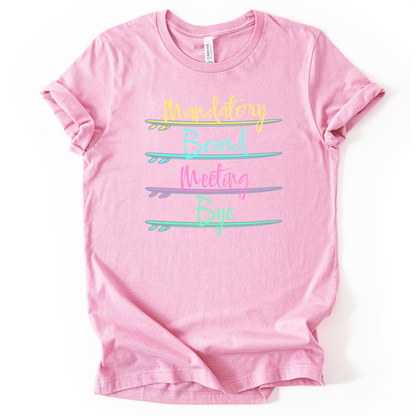 Surf themed beach graphic on a soft unisex heather pink graphic tee. The design features the phrase Mandatory Board Meeting Bye displayed across four stacked surfboards in bright summer colors including yellow, aqua, pink, and seafoam green. A lighthearted beach humor graphic that captures the feeling of skipping work for ocean time.