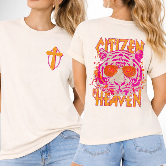 front and back image of a comfort color ivory tee.  pocket image is of a pink and mustard cross and the back is a large image that says Citizen of Heaven with a pink tiger wearing sunglasses