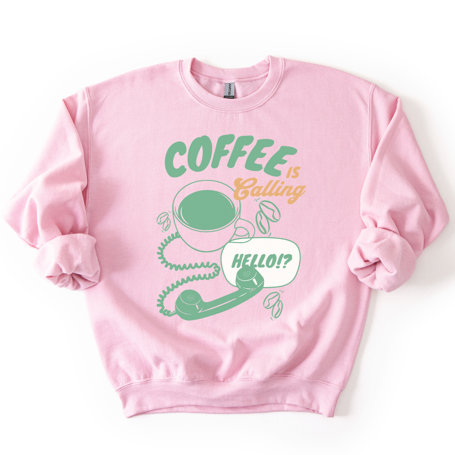 A light pink crewneck sweatshirt featuring a graphic print with the text 'COFFEE is Bailing' in green and orange, accompanied by a green coffee cup, coiled phone cord, green phone receiver, and a speech bubble that says 'HELLO!?' on a white background.