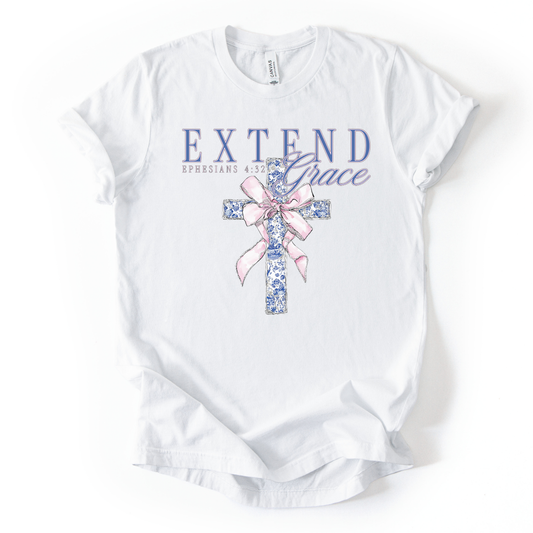 White t-shirt with floral cross and 'Extend Grace' text on a white background.The graphic features an illustrated cross filled with a blue floral pattern, tied with a soft pink ribbon bow at the center. Above the cross, the words “Extend Grace” appear in layered lettering, paired with the scripture reference Ephesians 4:32.