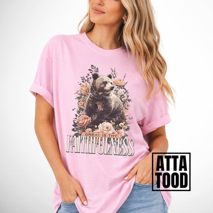 Woman wearing a pink t-shirt with a bear and floral design, text 'Great is thy Faithfulness', and 'ATTA TOOD' branding.