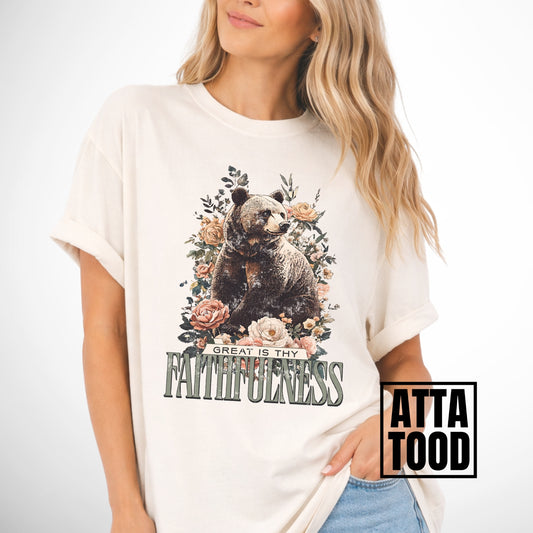 Person wearing a white t-shirt with a bear and floral design, text 'Great is thy faithfulness', and 'Atta Tood' branding.