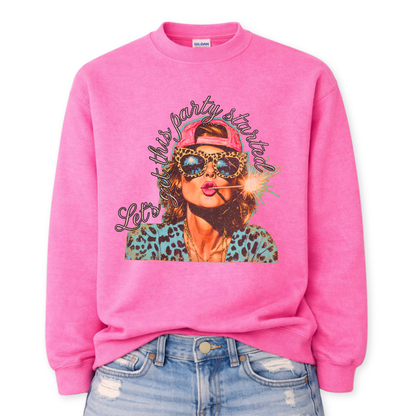 Patriotic Fourth of July graphic on a pink sweatshirt. The design features an illustrated woman wearing leopard-print sunglasses and a backward cap, holding a lit sparkler in her mouth. The artwork is layered with bold color contrasts, distressed textures, and playful script lettering that reads “Let’s Get This Party Started.” A high-energy patriotic design blending Americana attitude with modern pop-art style