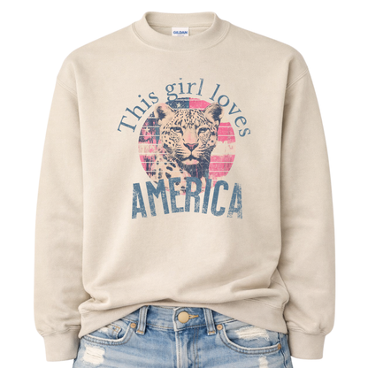 Beige sweatshirt with a graphic of a leopard and text 'This girl loves America' on a white background.