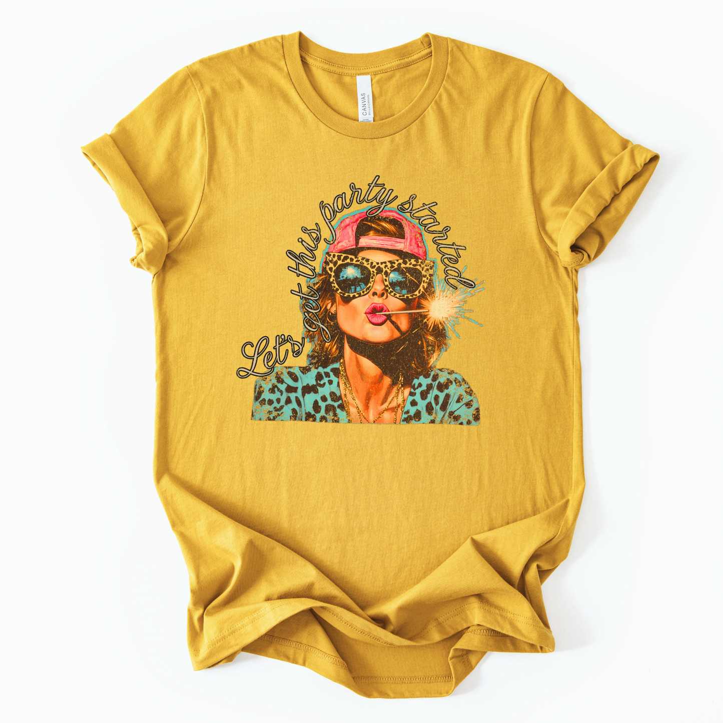 Mustard yellow Patriotic Fourth of July graphic on a white  t-shirt. The design features an illustrated woman wearing leopard-print sunglasses and a backward cap, holding a lit sparkler with fireworks reflected in the lenses. Curved script lettering adds a playful party vibe, blending bold Americana colors with a modern, fun-forward patriotic style ideal for summer celebrations.