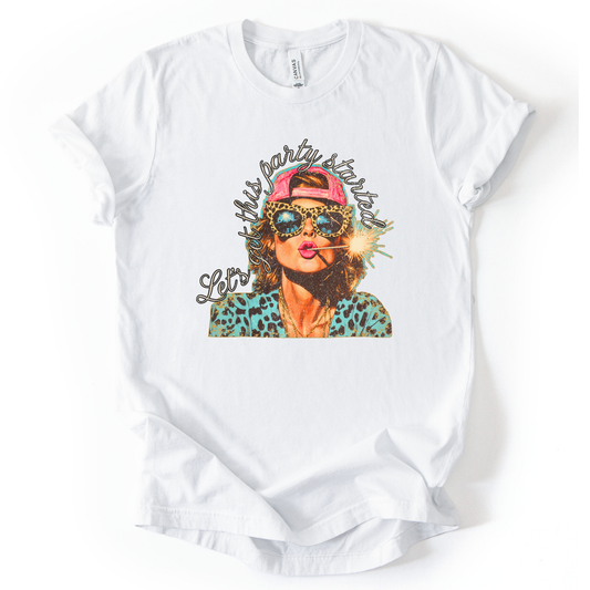 white Patriotic Fourth of July graphic on a white  t-shirt. The design features an illustrated woman wearing leopard-print sunglasses and a backward cap, holding a lit sparkler with fireworks reflected in the lenses. Curved script lettering adds a playful party vibe, blending bold Americana colors with a modern, fun-forward patriotic style ideal for summer celebrations.