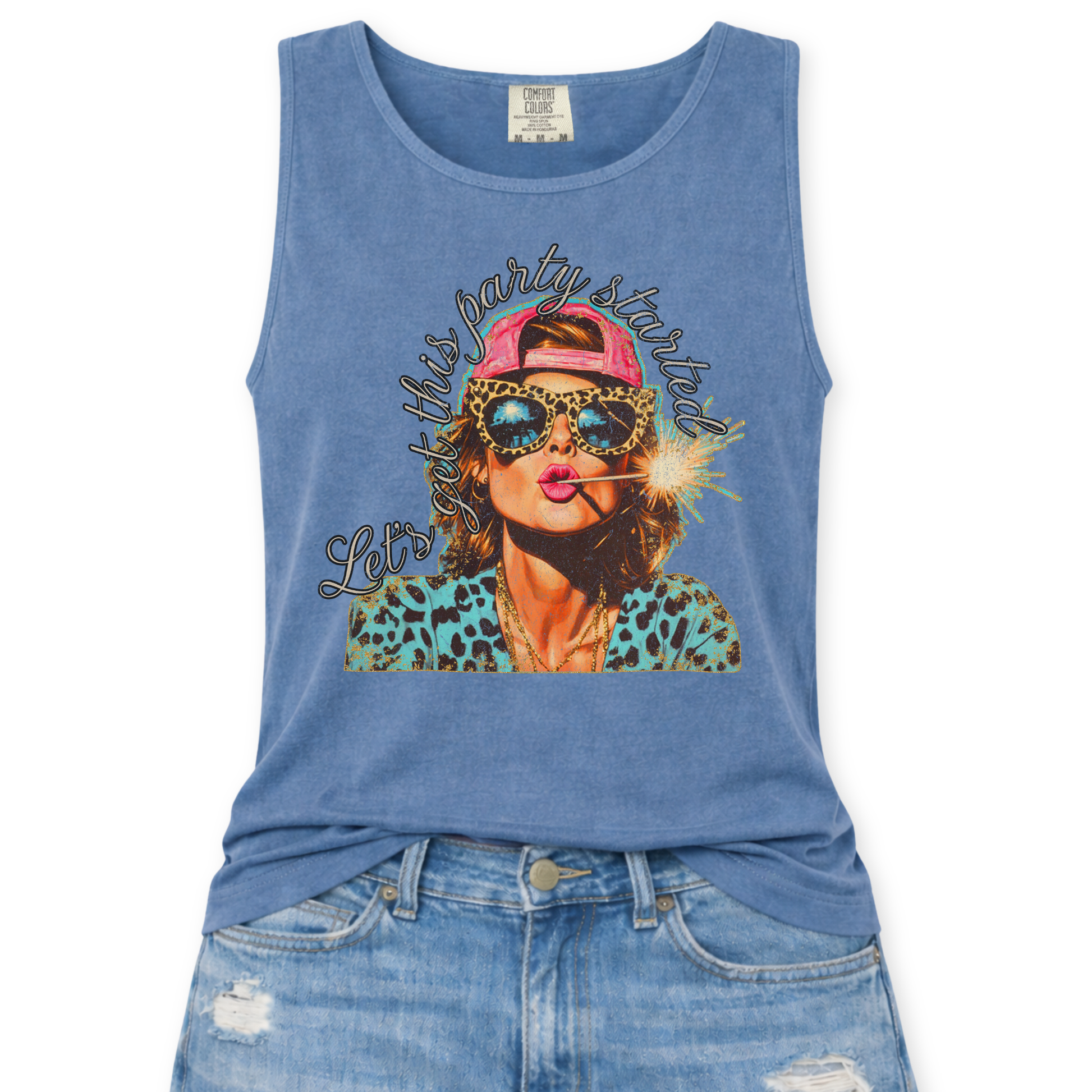 Blue Jean Comfort Colors tank top featuring a colorful patriotic graphic of a woman wearing leopard print sunglasses and a pink hat holding a sparkler with the phrase “Let’s Get This Party Started,” styled with light wash denim jeans.