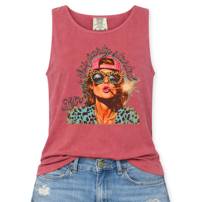 Crimson red Comfort Colors tank top featuring a colorful patriotic graphic of a woman wearing leopard print sunglasses and a pink hat holding a sparkler with the phrase “Let’s Get This Party Started,” styled with light wash denim jeans.