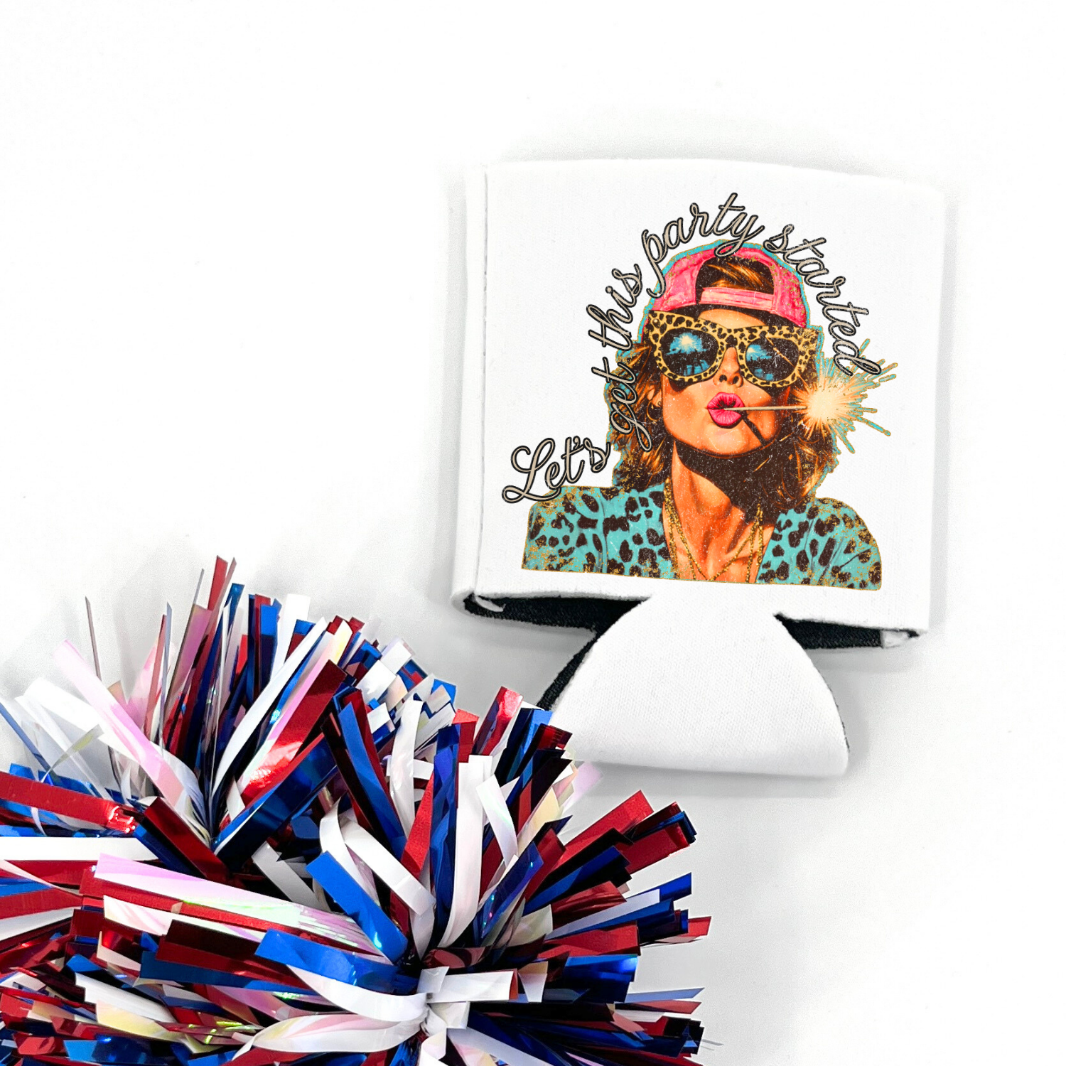 White collapsible can cooler displayed flat with a patriotic red, white, and blue pom pom in the foreground. The graphic features a woman wearing leopard print sunglasses, a pink backwards cap, and a teal leopard print top while holding a lit sparkler in her mouth. Script text reads “Let’s get this party started.” White can cooler with full color party-themed patriotic graphic.