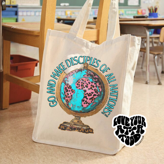 Jumbo canvas tote bag with hand-painted style globe graphic and “Go and Make Disciples” faith message, high-contrast artwork, Love your ATTA TOOD® brand mark, graphic printed on both sides.