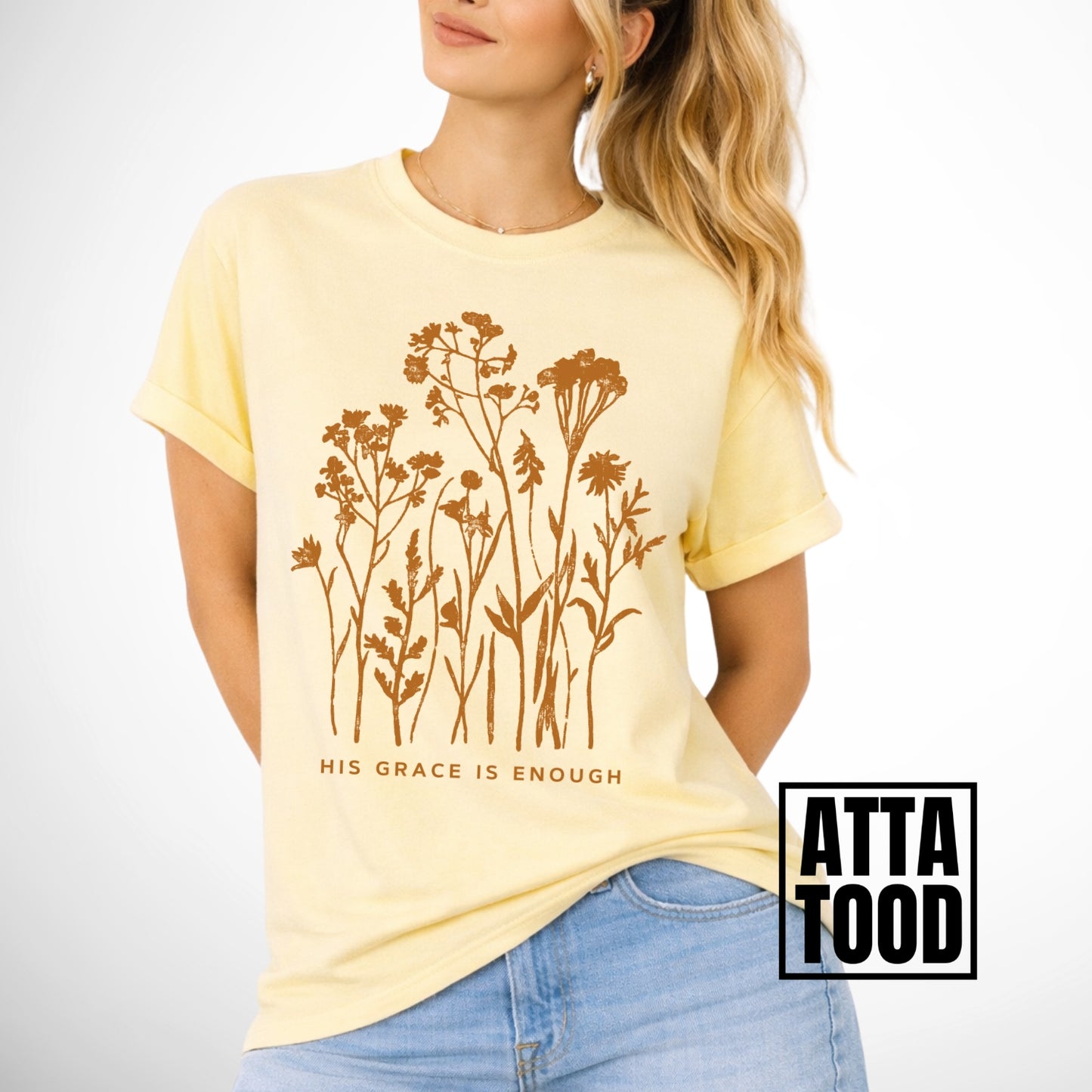 Woman wearing a yellow t-shirt with floral design and 'His Grace is Enough' text.