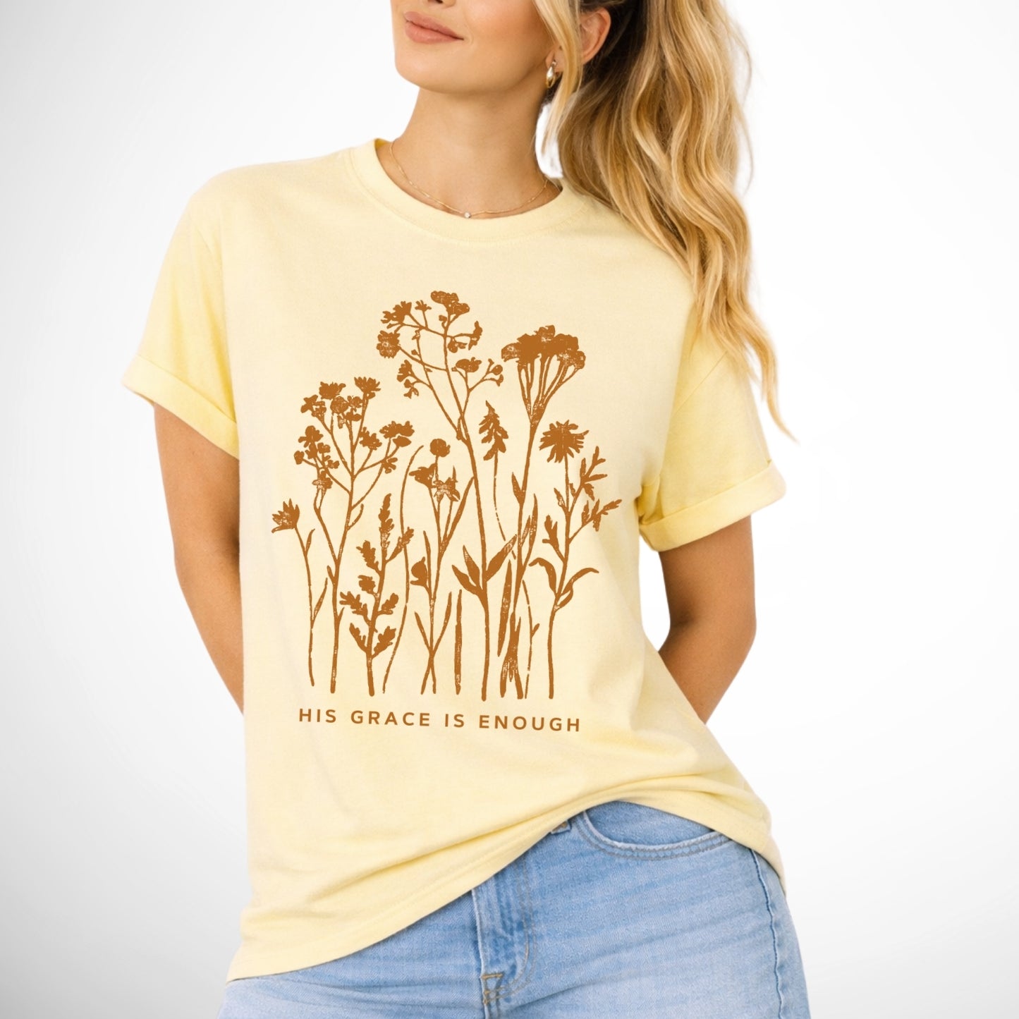 Woman wearing a yellow t-shirt with floral design and 'His Grace is Enough' text.