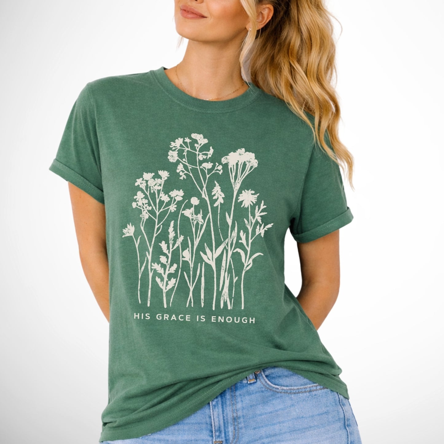 Woman wearing a green t-shirt with floral design and text on a white background that says His Grace is enought