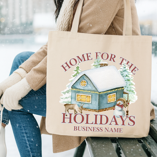 Canvas tote bag with a cabin, snowman and reindeer.  Tote says home for the holidays. Customizable tote with business name, city and state or both
