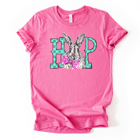 A pink graphic t-shirt printed on a Bella Canvas® premium retail-fit tee.

The graphic features an illustrated bunny centered between bold block letters, wearing a pink bow tie for a playful Easter touch. The bunny illustration is detailed with soft sketch-style lines, while the surrounding lettering adds a clean, modern contrast. The overall design feels fun, lighthearted, and spring-ready, making it ideal for Easter celebrations and everyday seasonal wear.