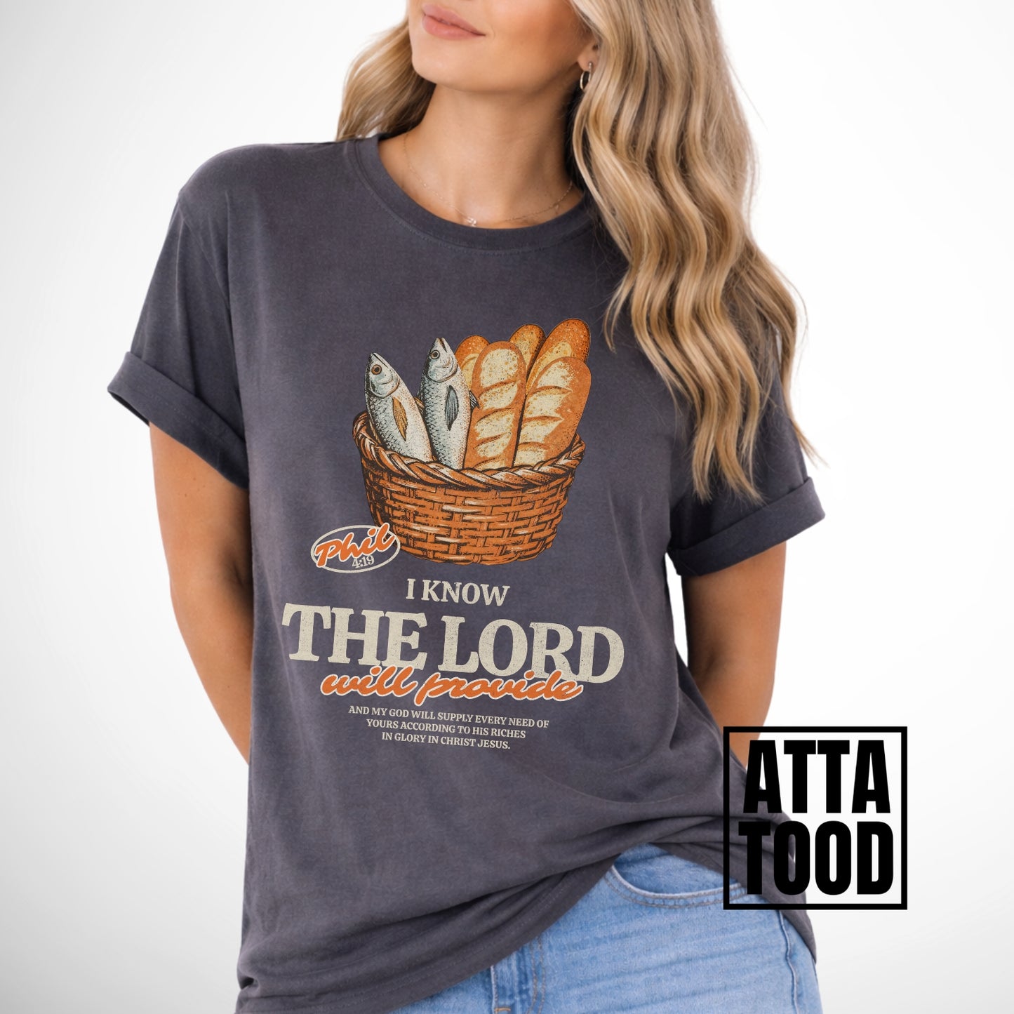 Person wearing a pepper t-shirt with a graphic design and text.  I know the Lord will provide featuring a basket of bread and fish referencing bible verse Philipians 4:19