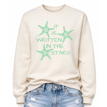 Sweet Cream Coastal sea life graphic on a classic crewneck sweatshirt. The design features three decorative starfish illustrations arranged around the phrase It Is Written In The Stars. Each starfish contains detailed swirl and sea life pattern elements that create a textured coastal look