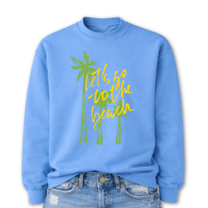 Tropical beach graphic on a classic blue crewneck sweatshirt. The design features three tall palm trees with the phrase Lets Go To The Beach layered across the center in a bold script style. The vertical palm tree layout creates a strong tropical silhouette that immediately communicates beach vacation style.