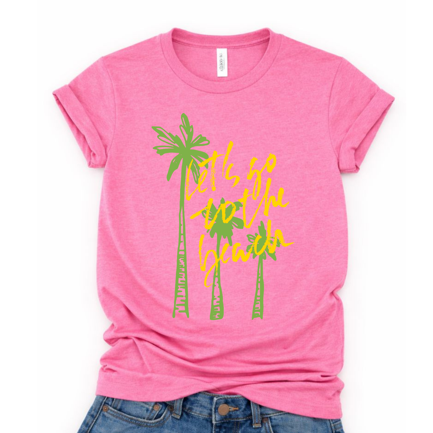 Summer beach graphic on a soft unisex Heather pink graphic tee. The design features three hand sketched palm trees in bright green with bold yellow script reading Lets go to the beach layered over the palms. 