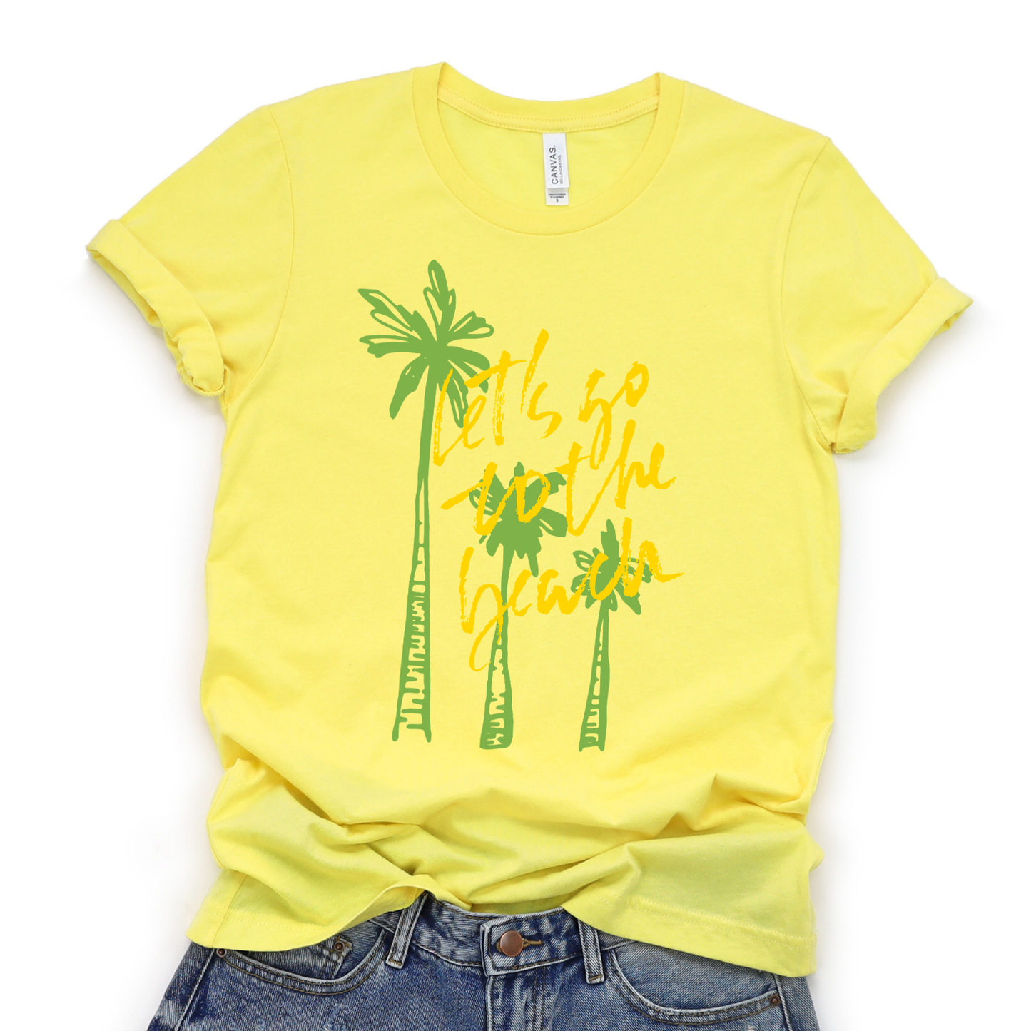 Summer beach graphic on a soft unisex Heather yellow graphic tee. The design features three hand sketched palm trees in bright green with bold yellow script reading Lets go to the beach layered over the palms. 