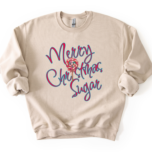 A beige crewneck sweatshirt featuring a colorful graphic on the front that reads 'Merry Christmas Sugar' in red and blue script with a lollipop illustration in the center.