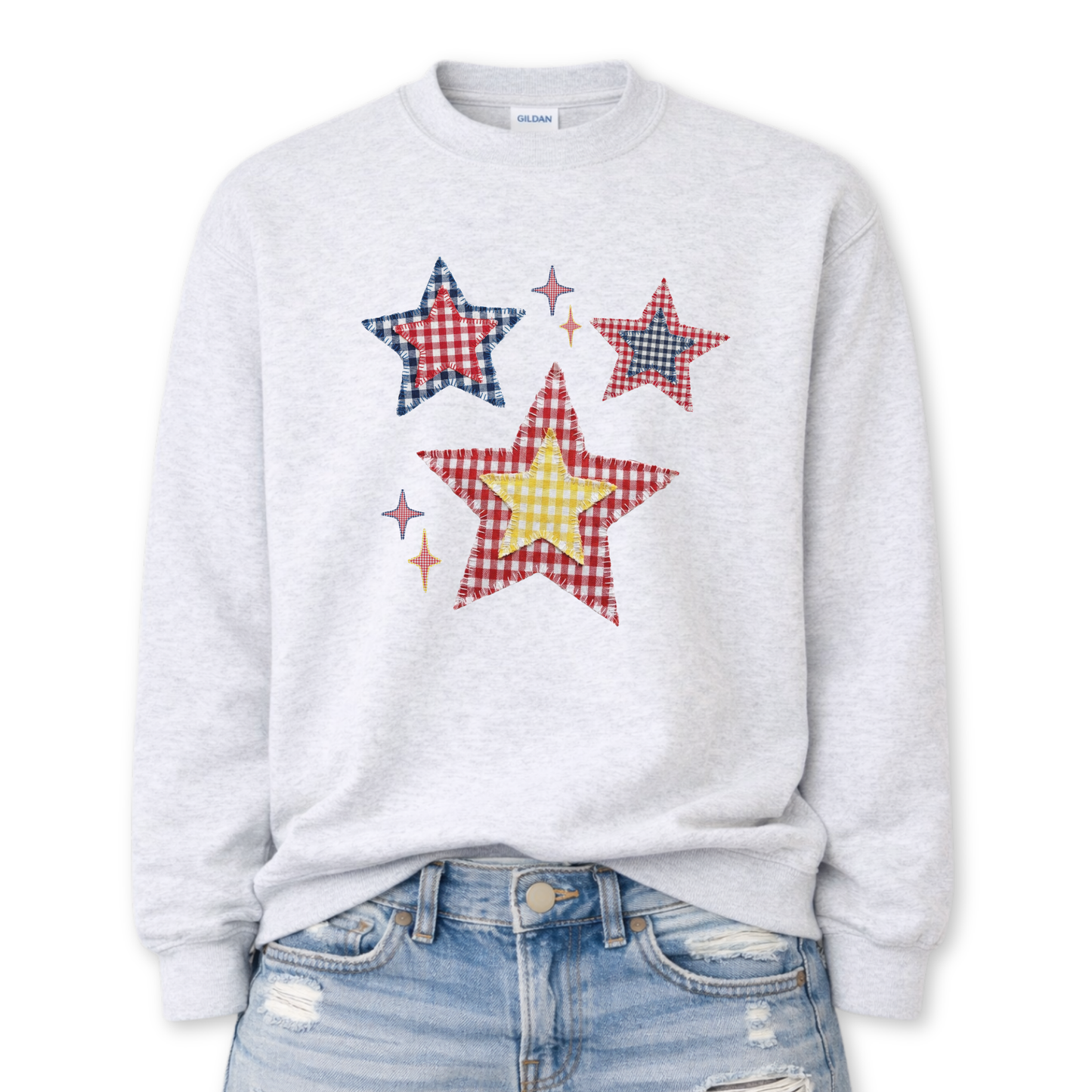 Patriotic patchwork star graphic on a gray sweatshirt. The design features a cluster of illustrated stars in varied sizes, each filled with classic red, white, and blue gingham-style patterns, including plaid and check textures. Small accent sparkles add movement while the layered patchwork look gives the graphic a cozy, Americana feel. A versatile patriotic design ideal for Fourth of July, summer events, and seasonal USA collections.