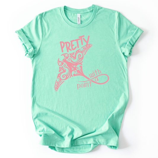 Coastal ocean graphic on a soft unisex mint green graphic tee. The design features a large manta ray illustration filled with decorative swirl and coastal pattern details that give the sea life artwork a textured, ocean inspired look. The phrase Pretty With A Point appears integrated into the graphic, with bold lettering above the manta ray and flowing script below, creating a balanced coastal themed layout.