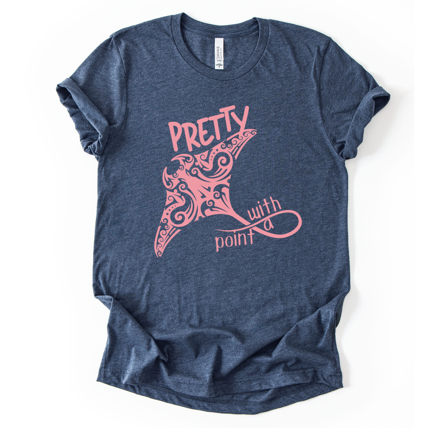 Coastal ocean graphic on a soft unisex heather navy graphic tee. The design features a large manta ray illustration filled with decorative swirl and coastal pattern details that give the sea life artwork a textured, ocean inspired look. The phrase Pretty With A Point appears integrated into the graphic, with bold lettering above the manta ray and flowing script below, creating a balanced coastal themed layout.