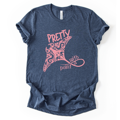 Coastal ocean graphic on a soft unisex heather navy graphic tee. The design features a large manta ray illustration filled with decorative swirl and coastal pattern details that give the sea life artwork a textured, ocean inspired look. The phrase Pretty With A Point appears integrated into the graphic, with bold lettering above the manta ray and flowing script below, creating a balanced coastal themed layout.