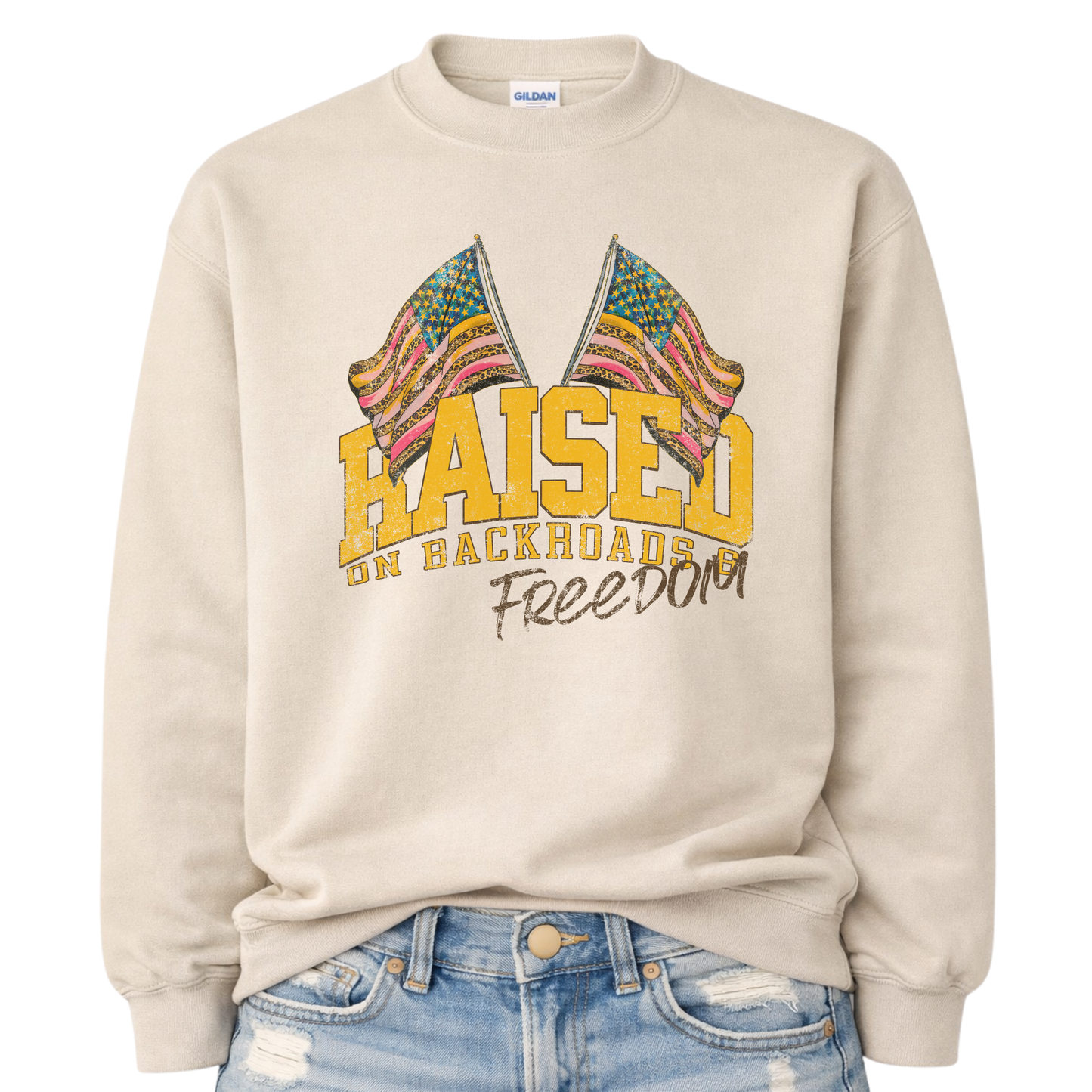 Beige sweatshirt with colorful graphic and text 'Raised on Backroads Freedom' on a white background.