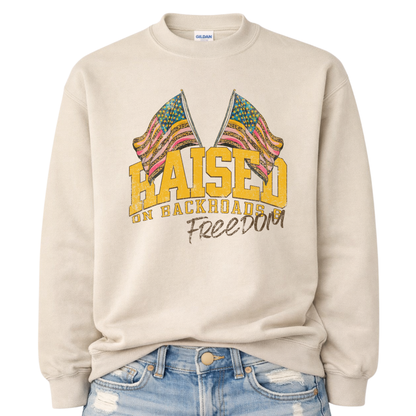 Beige sweatshirt with colorful graphic and text 'Raised on Backroads Freedom' on a white background.