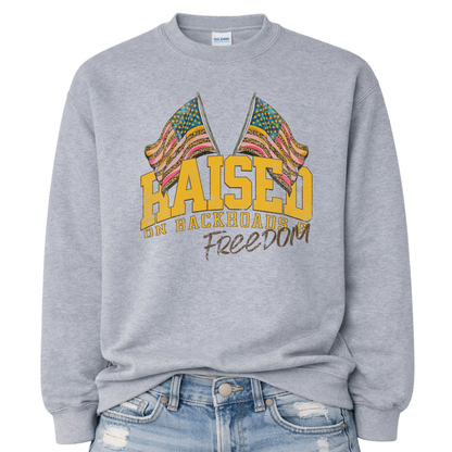 Gray sweatshirt with colorful flag design and text 'Raised on Backroads Freedom' on a white background.