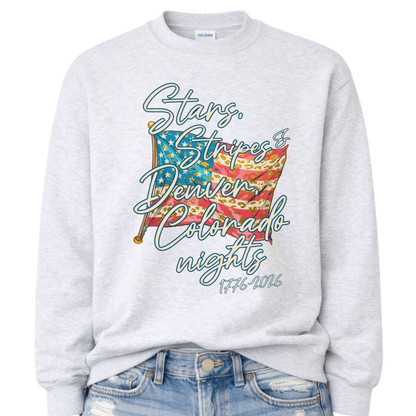 Patriotic stars and stripes graphic on a gray sweatshirt. The artwork shows a waving American flag with stars, striped details, and leopard-print accents, paired with script lettering that reads “Stars, Stripes & ___ Nights” plus “1776–2026” for a bold Fourth of July and summer patriotic look. Customizable location option: add any City or State (up to 30 characters) to make it a hometown, vacation spot, or event-ready USA piece.