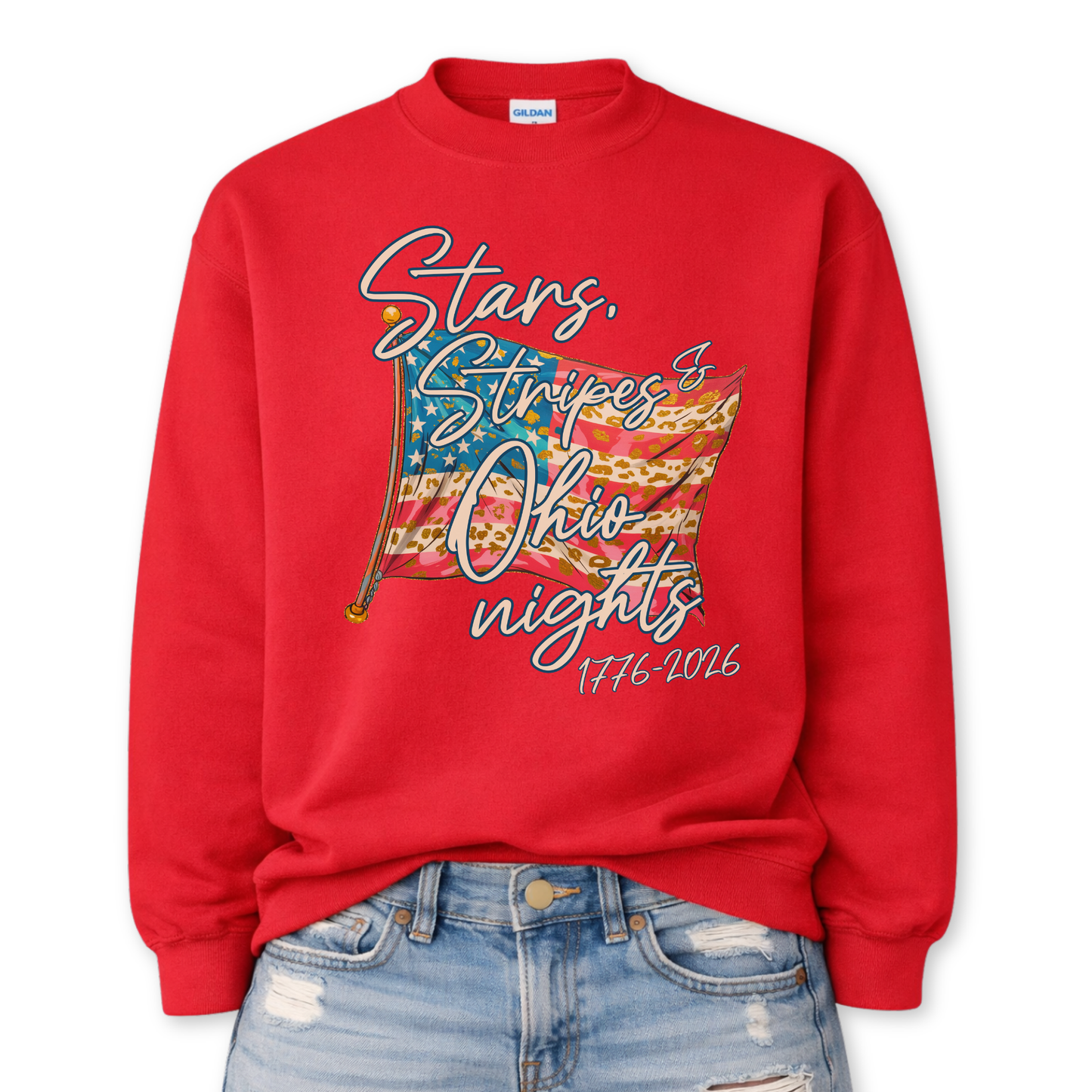 Patriotic stars and stripes graphic on a red sweatshirt. The artwork shows a waving American flag with stars, striped details, and leopard-print accents, paired with script lettering that reads “Stars, Stripes & ___ Nights” plus “1776–2026” for a bold Fourth of July and summer patriotic look. Customizable location option: add any City or State (up to 30 characters) to make it a hometown, vacation spot, or event-ready USA piece.