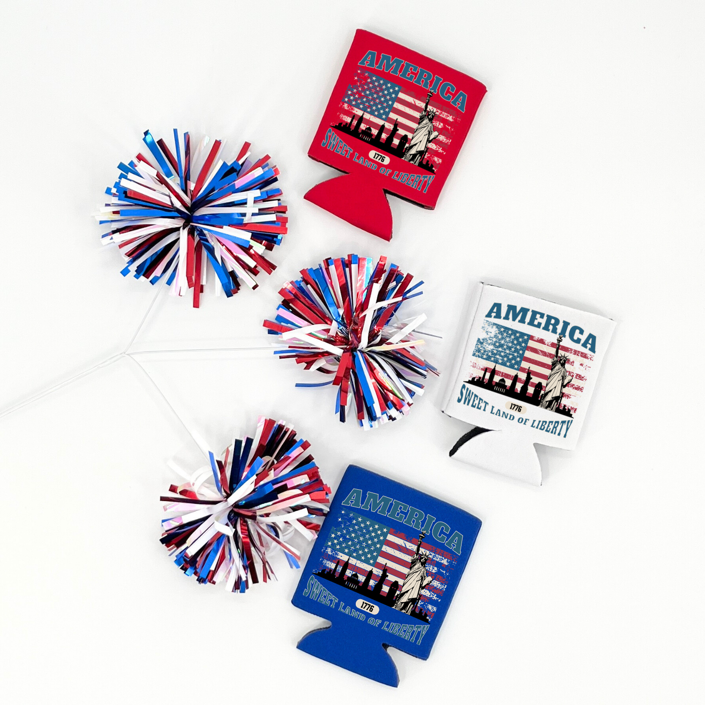 Assorted patriotic collapsible can coolers in red, white, and royal blue featuring a Statue of Liberty and American flag graphic with the wording “America Sweet Land of Liberty 1776,” styled with red, white, and blue pom poms on a white background.