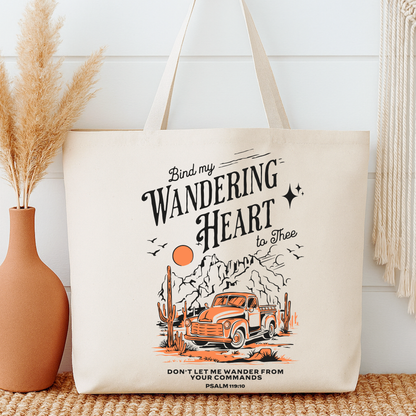 Tote bag with a truck and cactus design, text 'Bind my wandering heart to thee', next to a vase with dried plants.