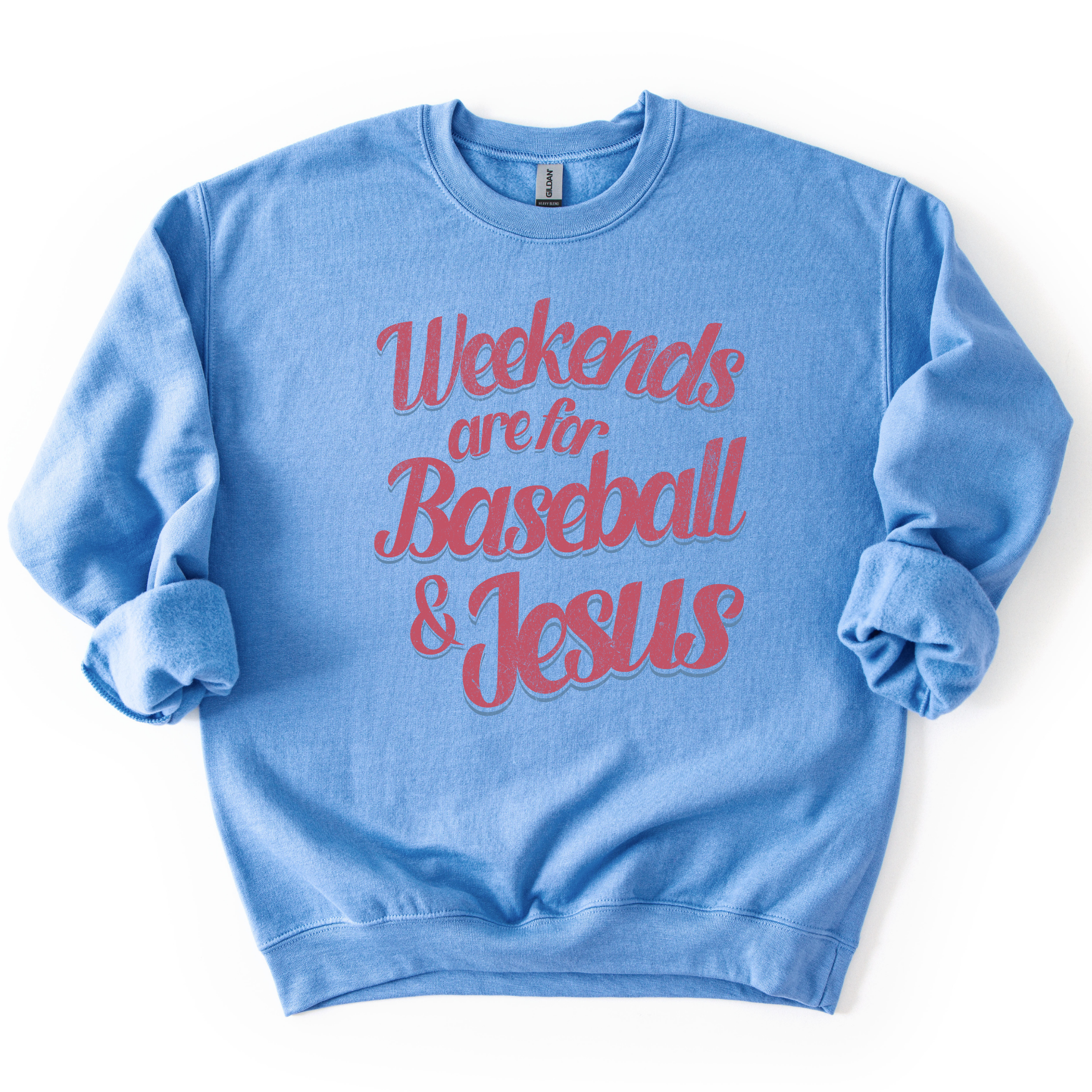 blue-colored crewneck sweatshirt with pink and blue retro script text reading “Weekends are for Baseball & Jesus,” styled flat with sleeves scrunched