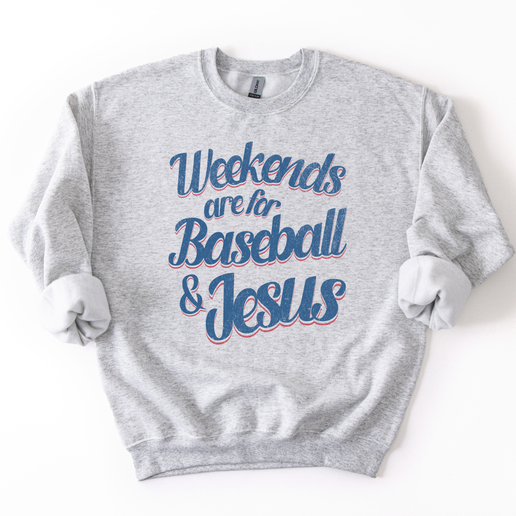 ash-colored crewneck sweatshirt with pink and blue retro script text reading “Weekends are for Baseball & Jesus,” styled flat with sleeves scrunched