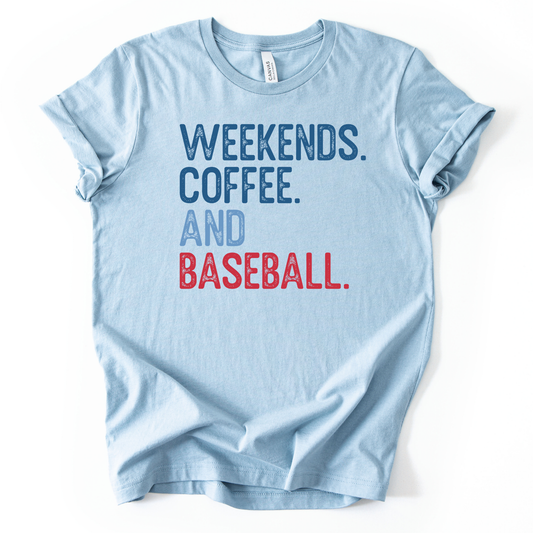 Heather baby blue graphic t-shirt with distressed text that reads “WEEKENDS. COFFEE. AND BASEBALL.” in navy, light blue, and red, laid flat with rolled sleeves.